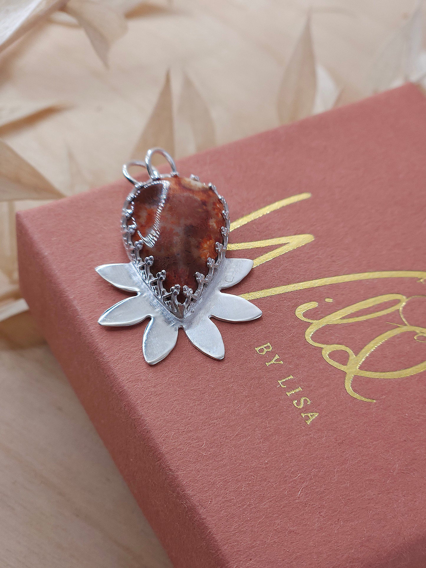A front view of the red fossil coral necklace, showing off the silver half flower design.