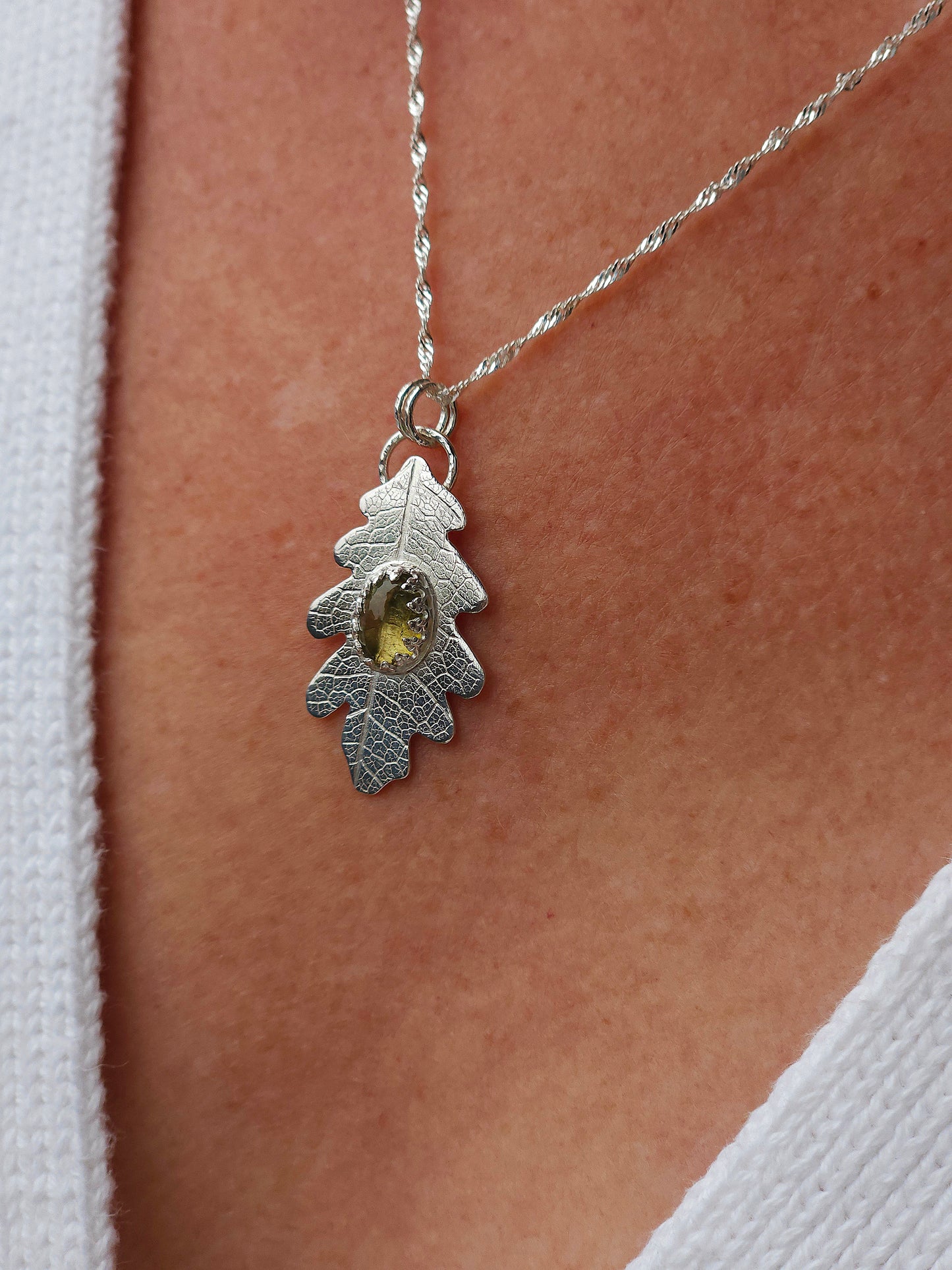 A sterling silver leaf print necklace with a neutral coloured tourmaline gemstone.