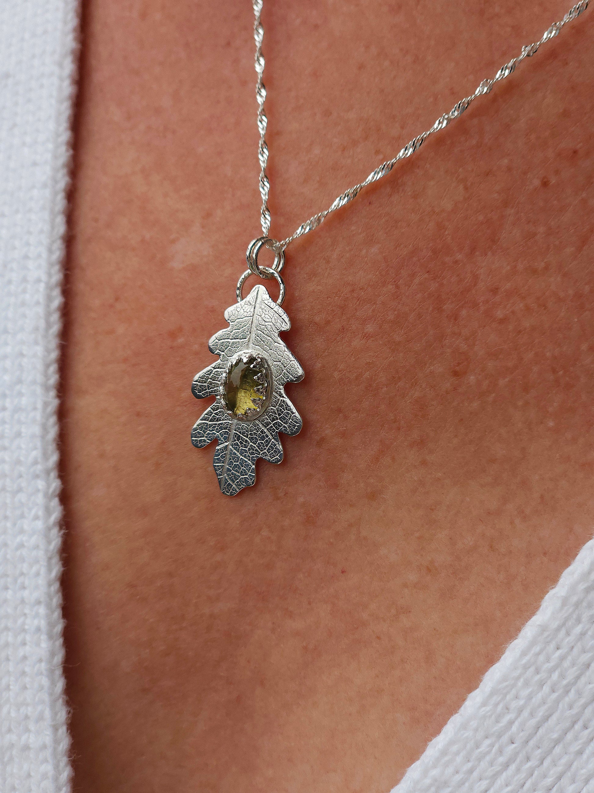 A sterling silver leaf print necklace with a neutral coloured tourmaline gemstone.