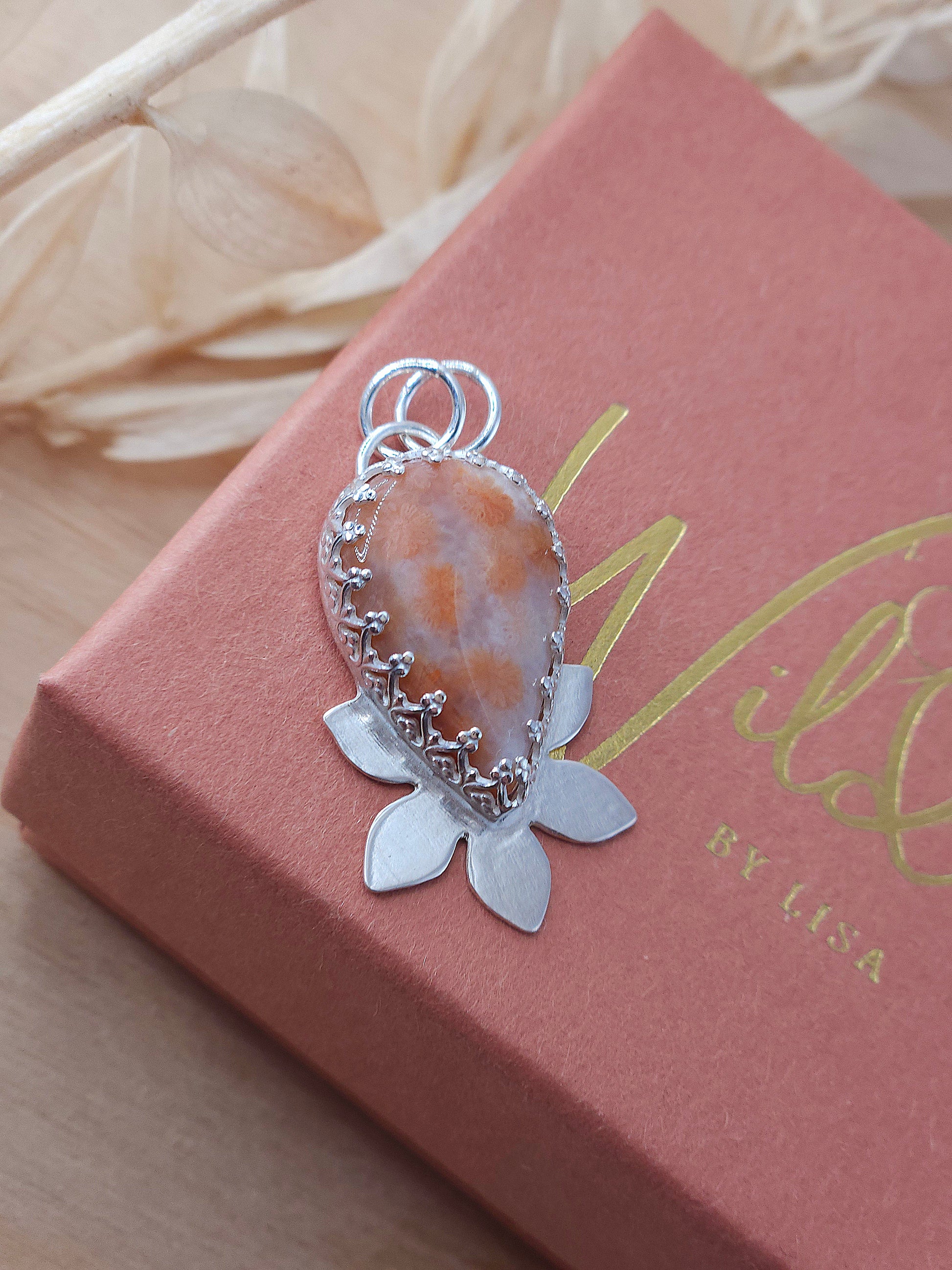 A peachy pink fossilised coral necklace with a half flower design.