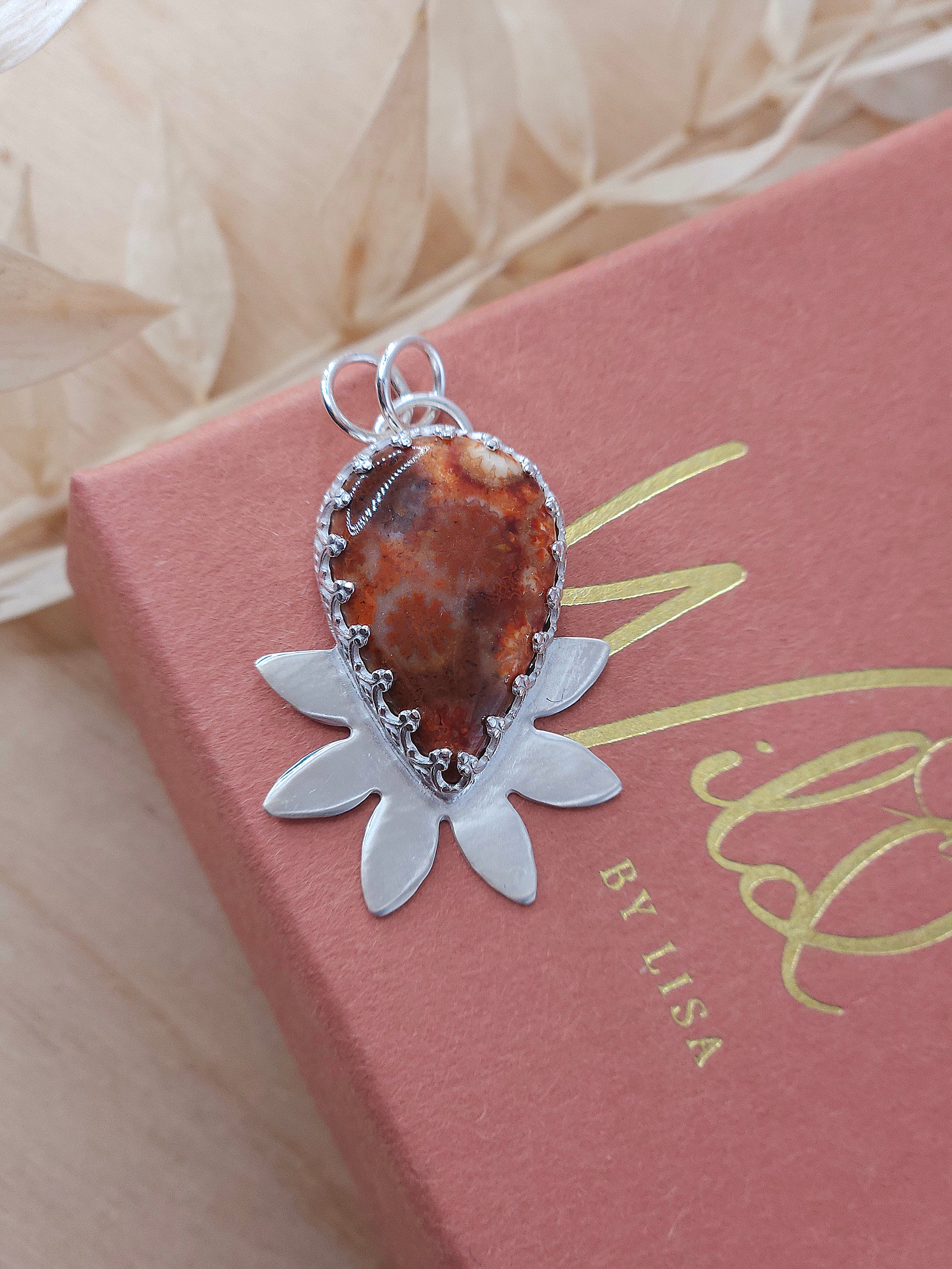 Silver half flower design pendant featuring a red fossilised coral gemstone.
