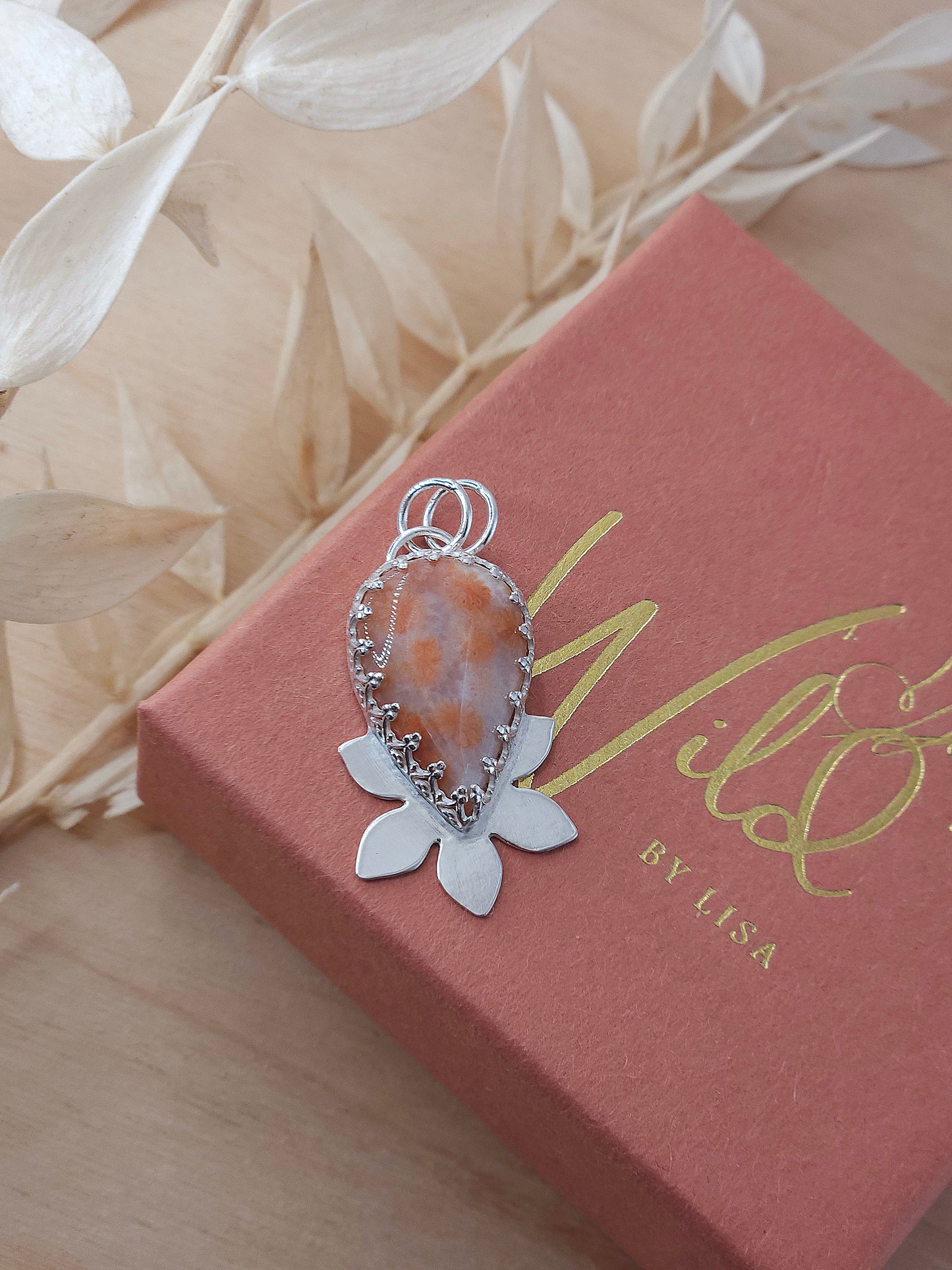 A sterling silver flower pendant featuring a peachy pink fossil coral gemstone.