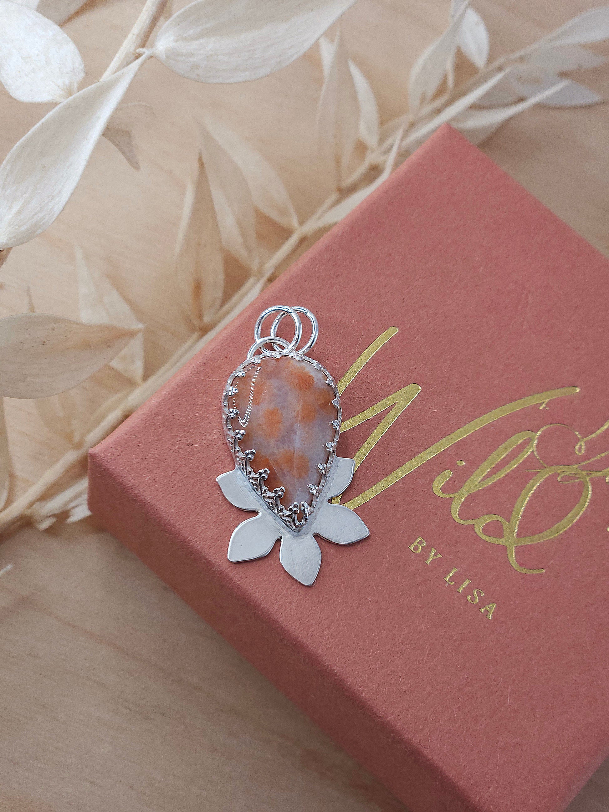 A sterling silver flower pendant featuring a peachy pink fossil coral gemstone.