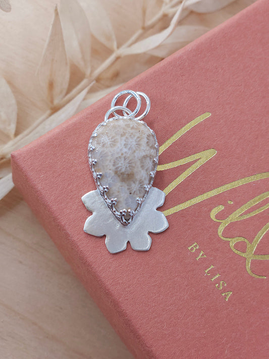 A pear shape fossilised coral gemstone pendant with a half flower design. Handmade in sterling silver.