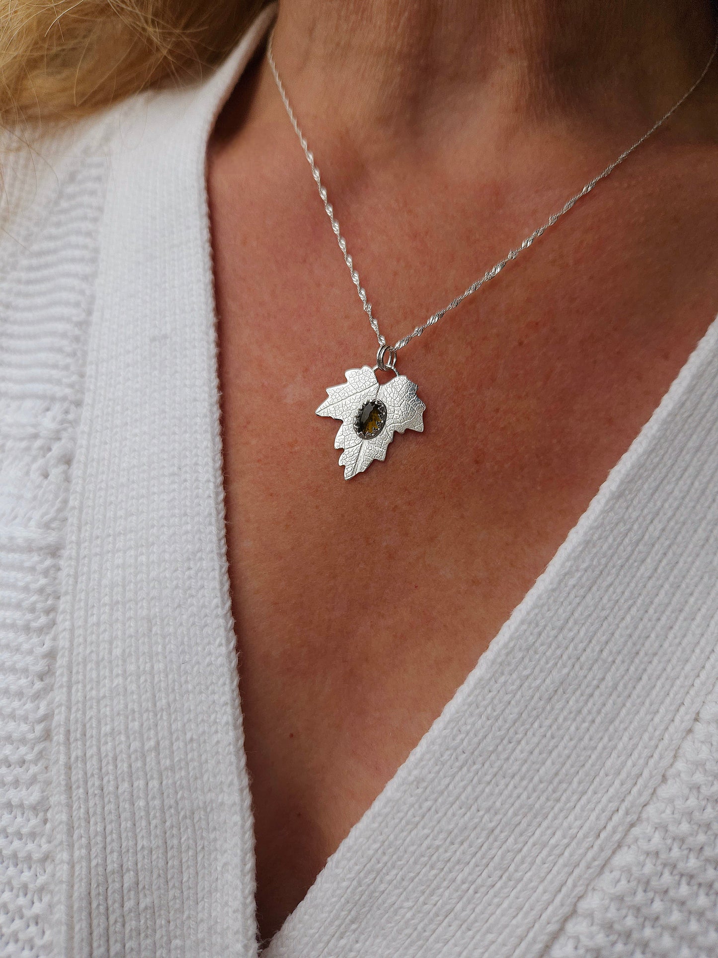 The brown tourmaline leaf necklace worn with a white cardigan.