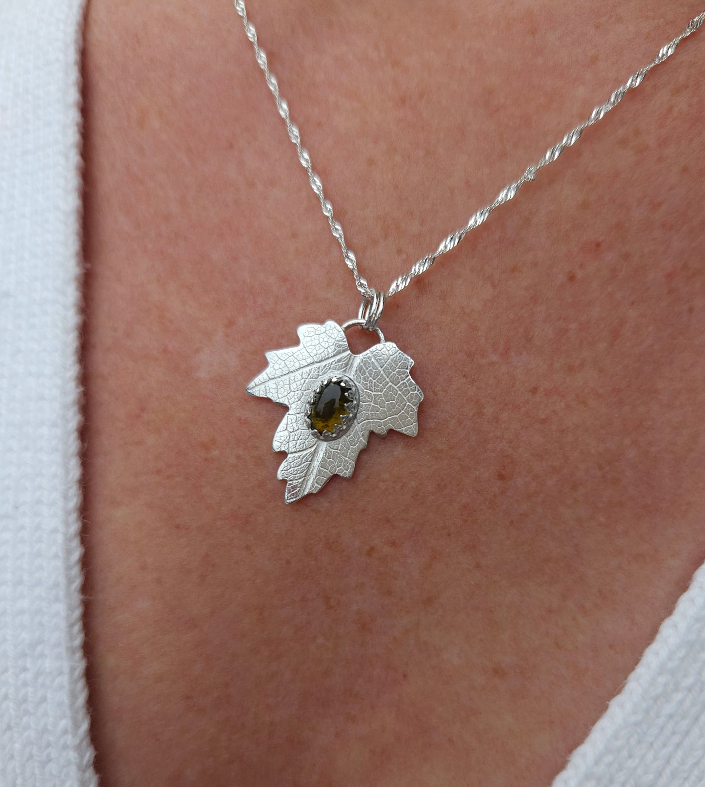 A sterling silver leaf pendant with a brown tourmaline gemstone.