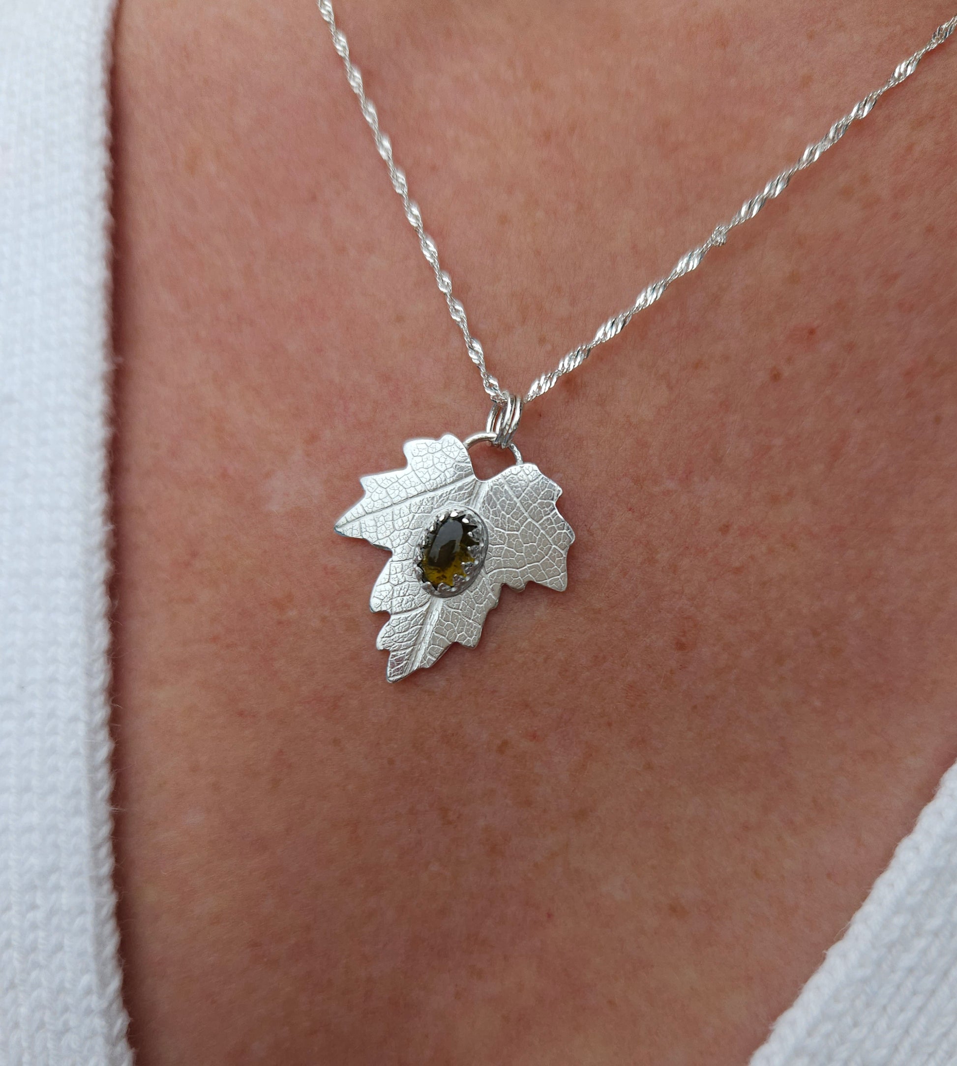 A sterling silver leaf pendant with a brown tourmaline gemstone.