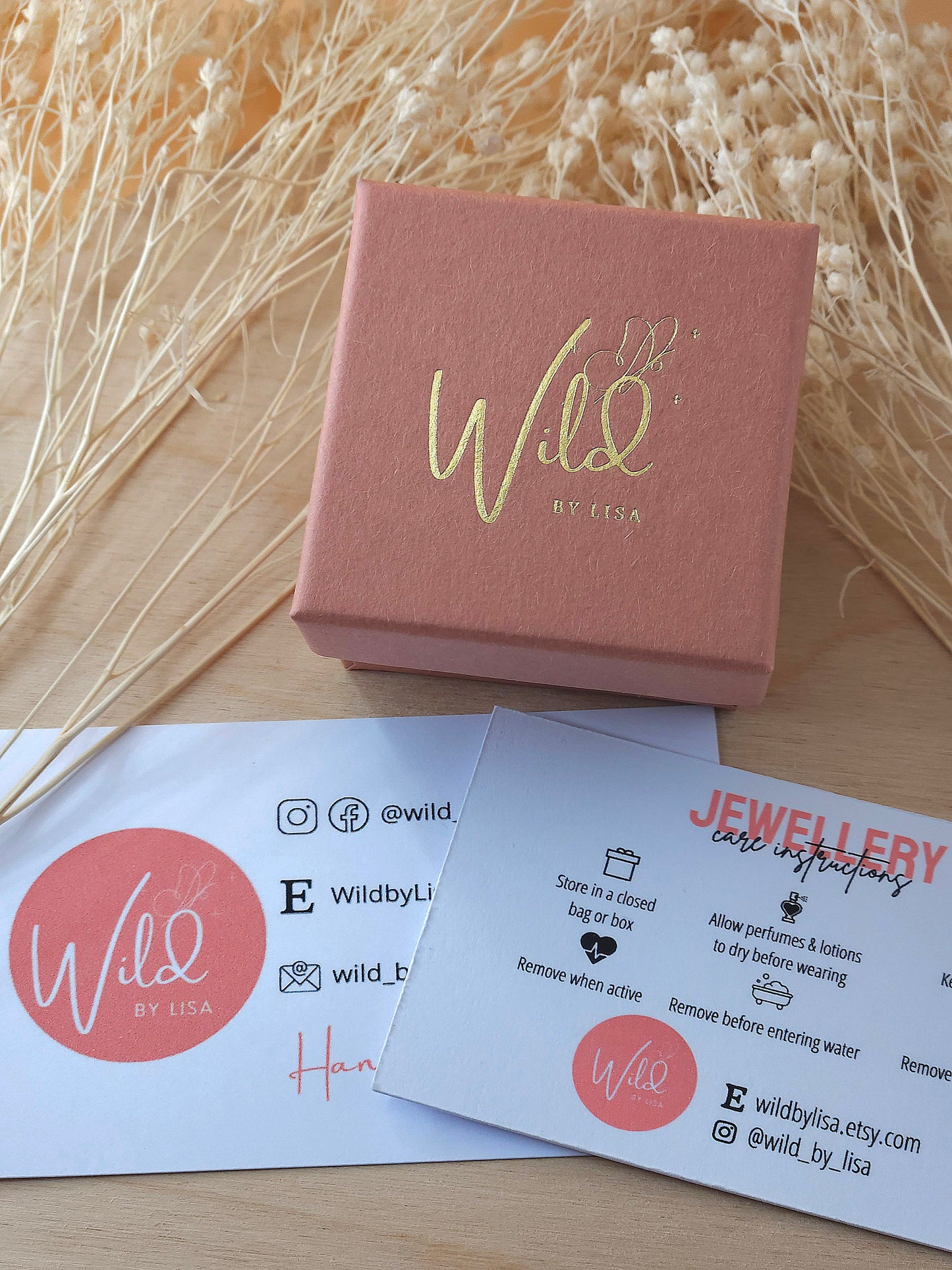 A photo showing a Wild by Lisa gift box, jewellery care card and business card.