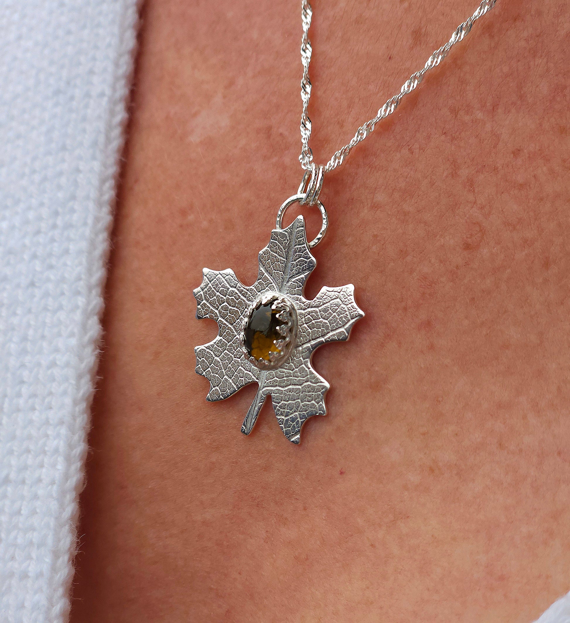 A sterling silver leaf necklace being worn.