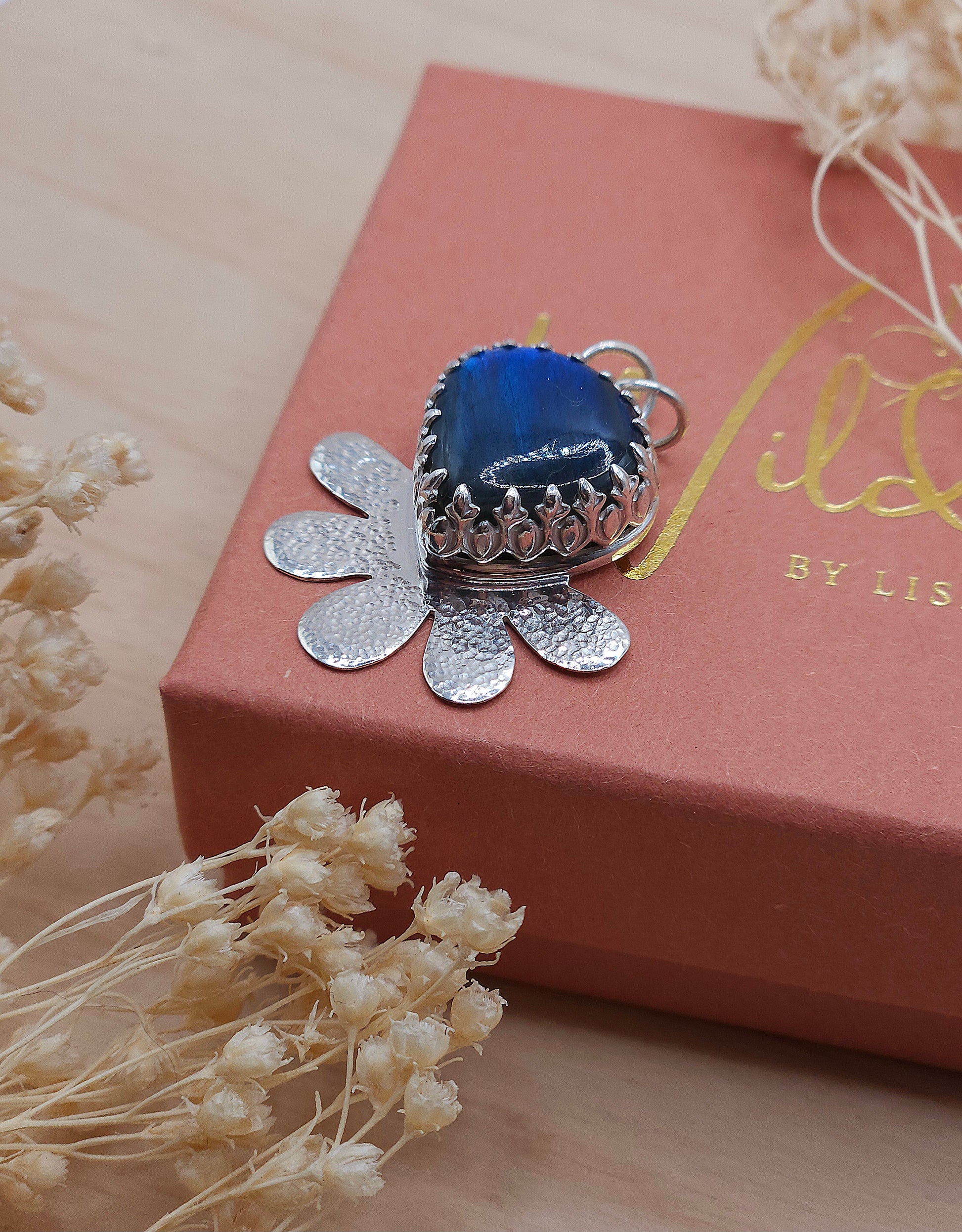 A side view of the silver flower necklace showing the decorative bezel that holds the Labradorite gemstone in place.