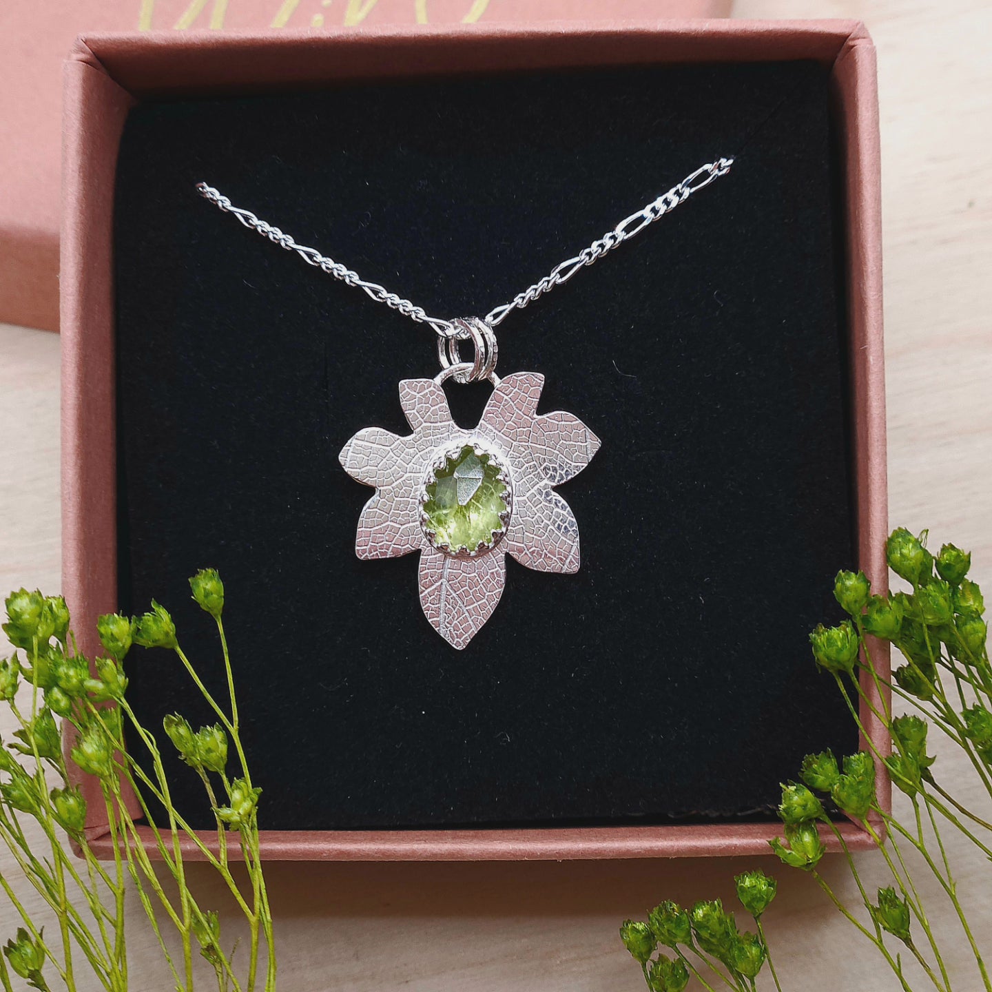 A sterling silver leaf necklace featuring a natural Peridot gemstone. Shown in a gift box.