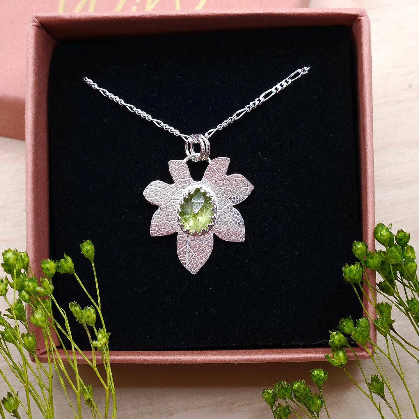 A sterling silver leaf necklace featuring a natural Peridot gemstone. Shown in a gift box.