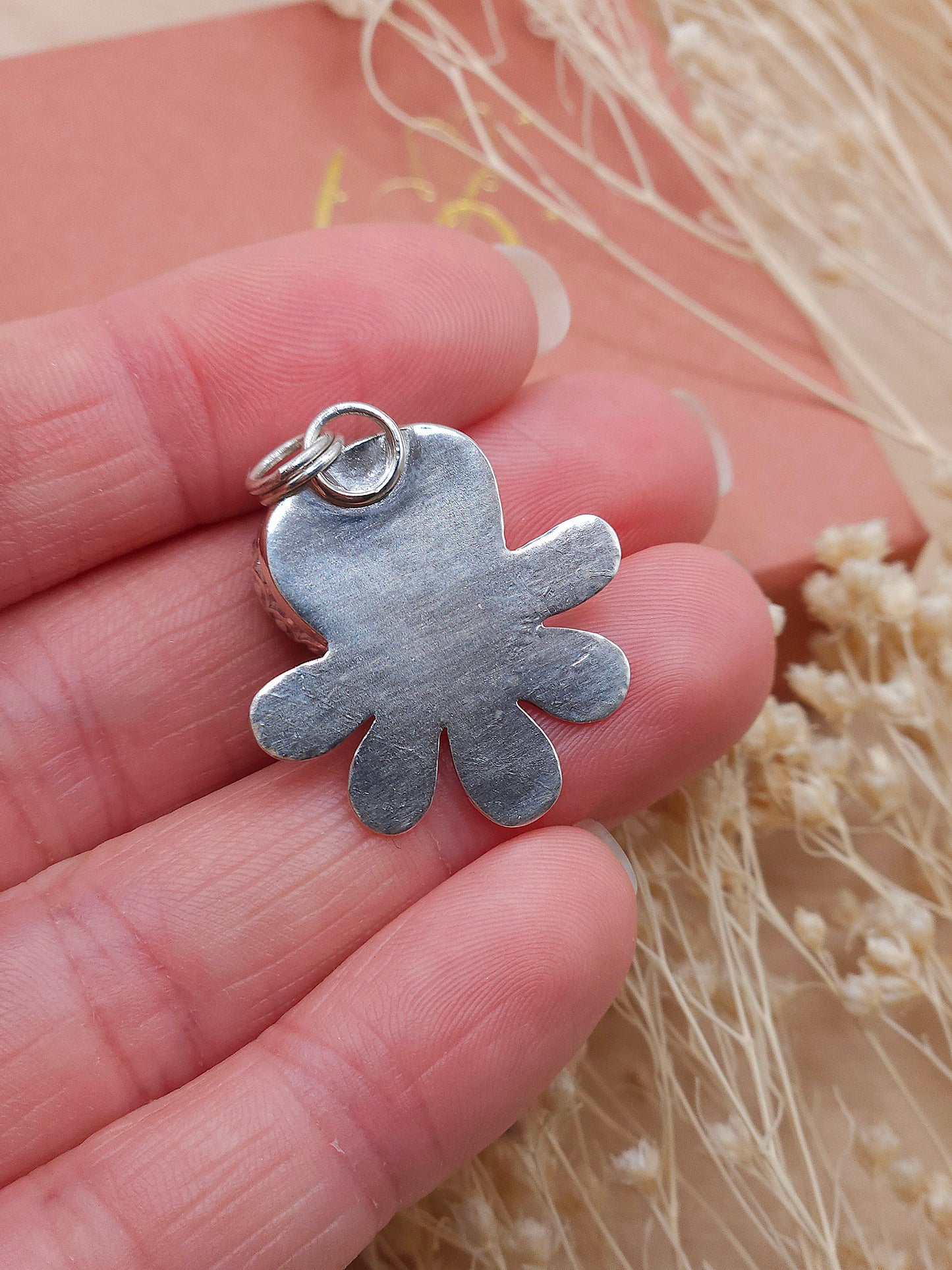 A view of the back of the silver flower pendant with a natural texture.