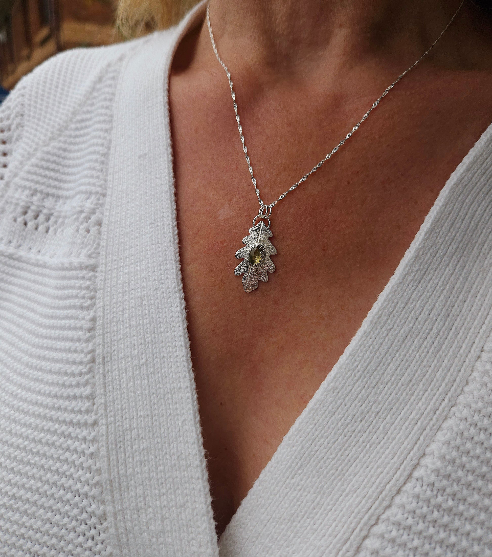 A model wearing the silver tourmaline leaf pendant with a white cardigan.
