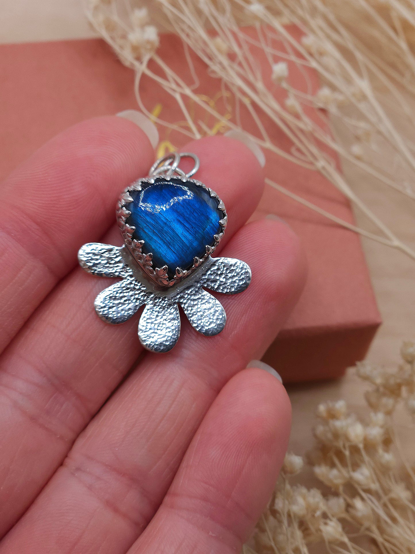 A close up of the Labradorite hammered flower pendant, showing the blue flash appearance of the gemstone.