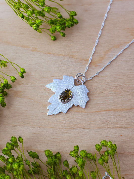 A sterling silver leaf pendant featuring a brown Tourmaline gemstone.