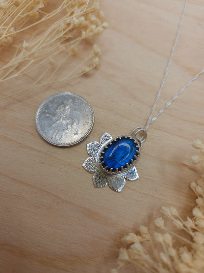 A size reference for the silver flower necklace with blue Labradorite gemstone. Roughly the size of a 10 pence coin.