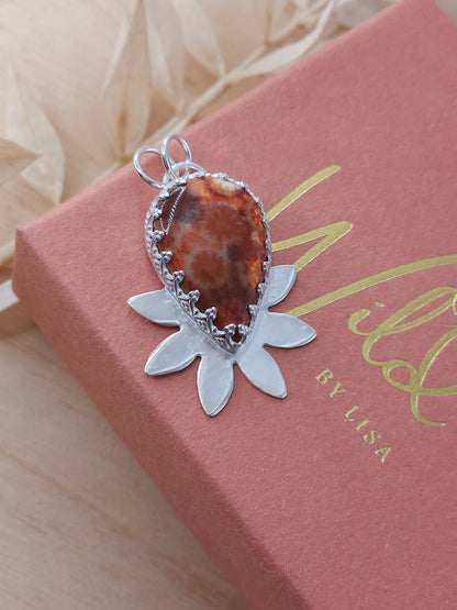 A sterling silver flower necklace featuring a natural red fossilised coral gemstone.