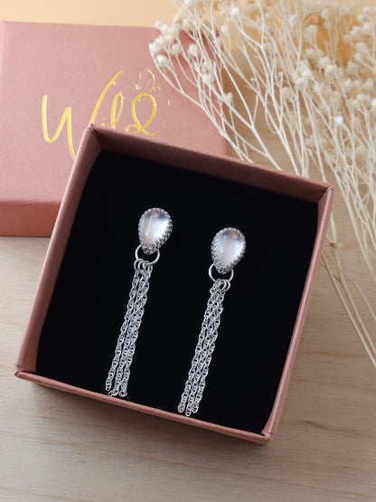 A pair of silver chain dangle earrings with rose quartz gemstones displayed in an open gift box on a black foam insert.
