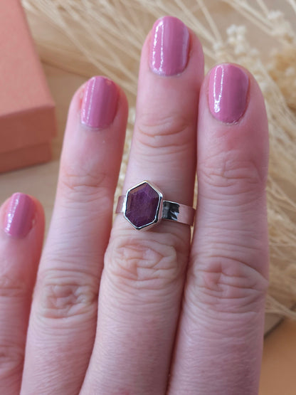 A sterling silver pinkie ring with ruby gemstone displayed on a finger.