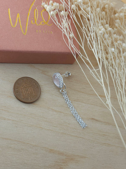 A single silver earring with rose quartz gemstone lay next to a one pence coin to show the size.