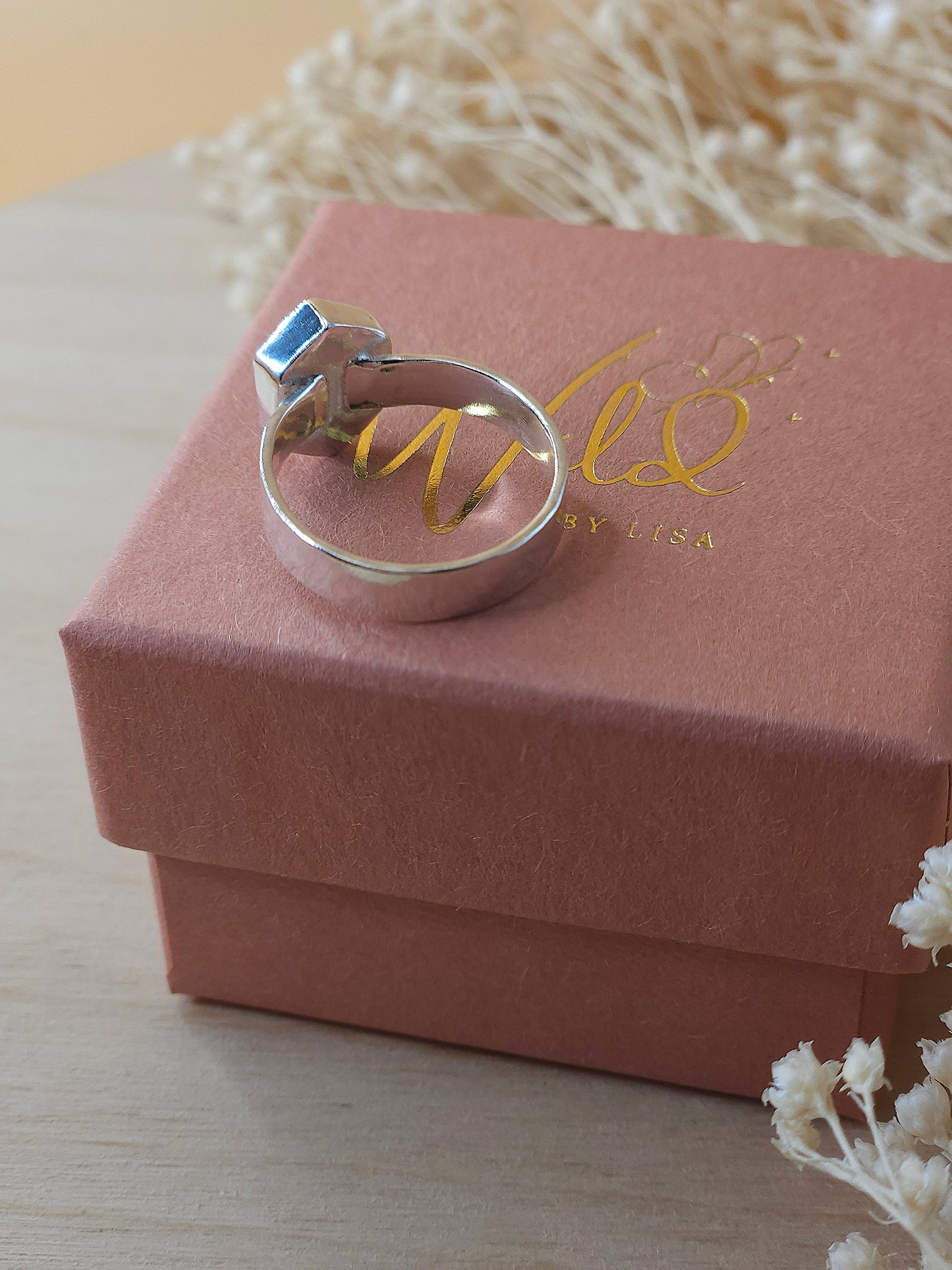 A sterling silver pinkie ring displayed on a gift box showing the back of the ring and gemstone setting.