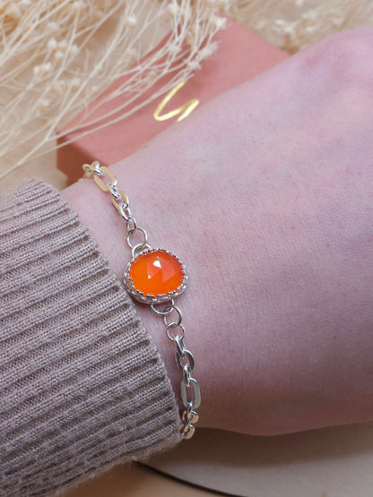 An orange carnelian gemstone link chain bracelet worn on a wrist.