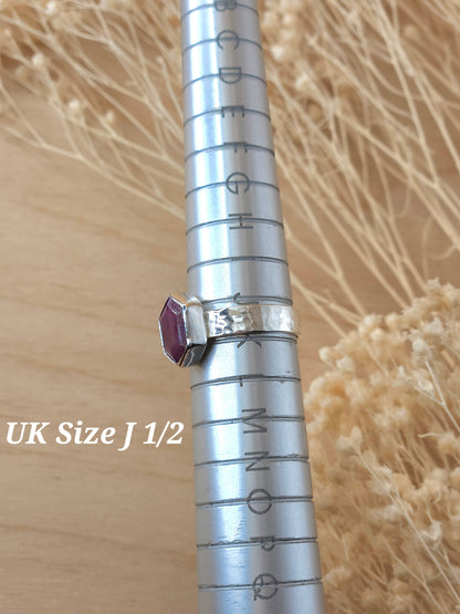 A jewellers ring mandrel holding  a silver gemstone ring which sits at UK size J 1/2.