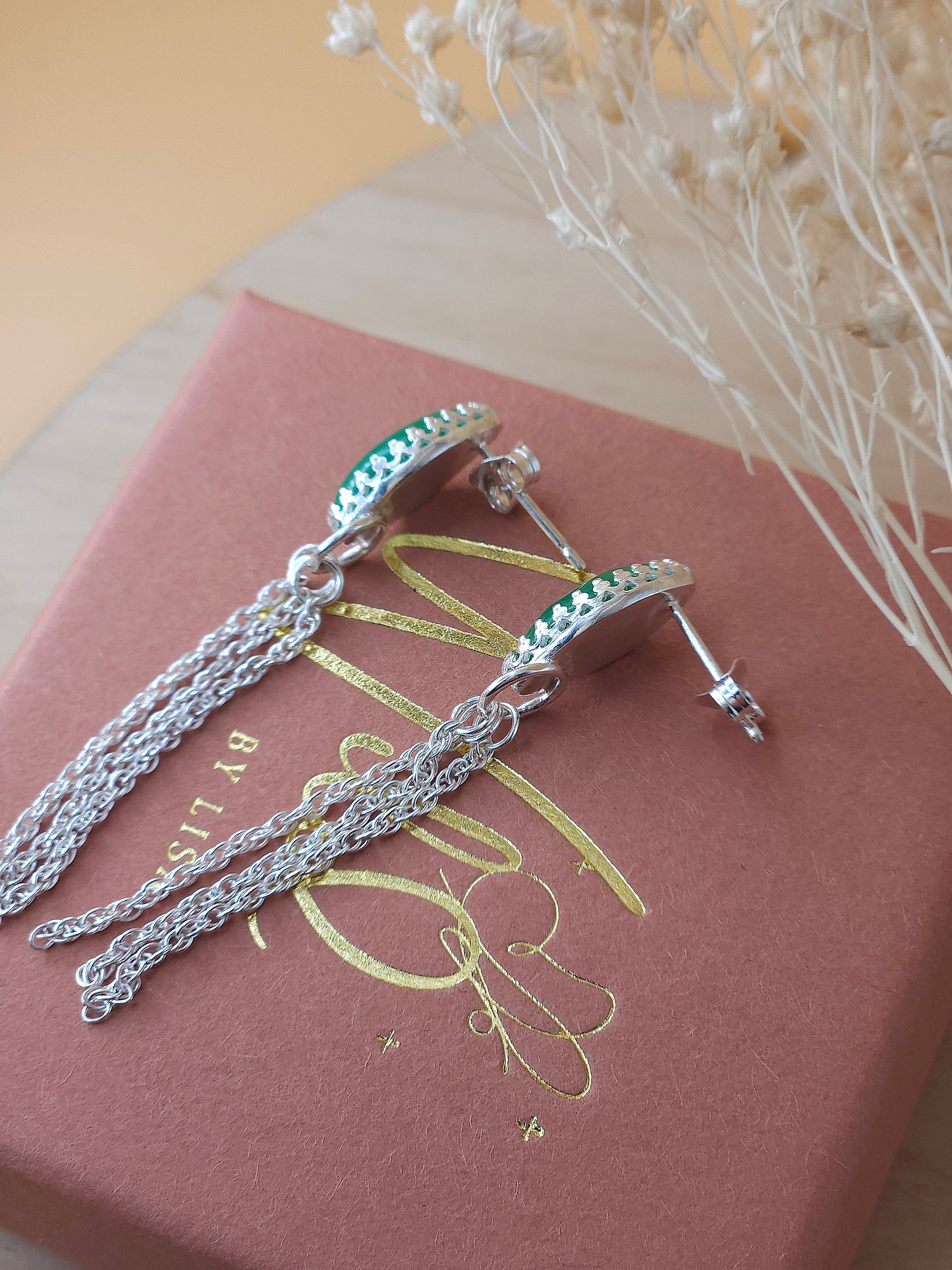 A pair of silver chain dangle earrings lay on a gift box showing the side view.