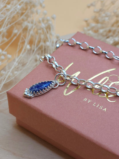 A silver link chain bracelet with a Lapis Lazuli gemstone charm, displayed on a gift box with the brand name 'Wild by Lisa'.