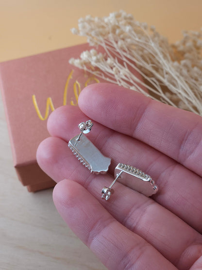 A hand holding a pair of sterling silver gemstone stud earrings. Showing the back view of the earrings with butterfly backings.