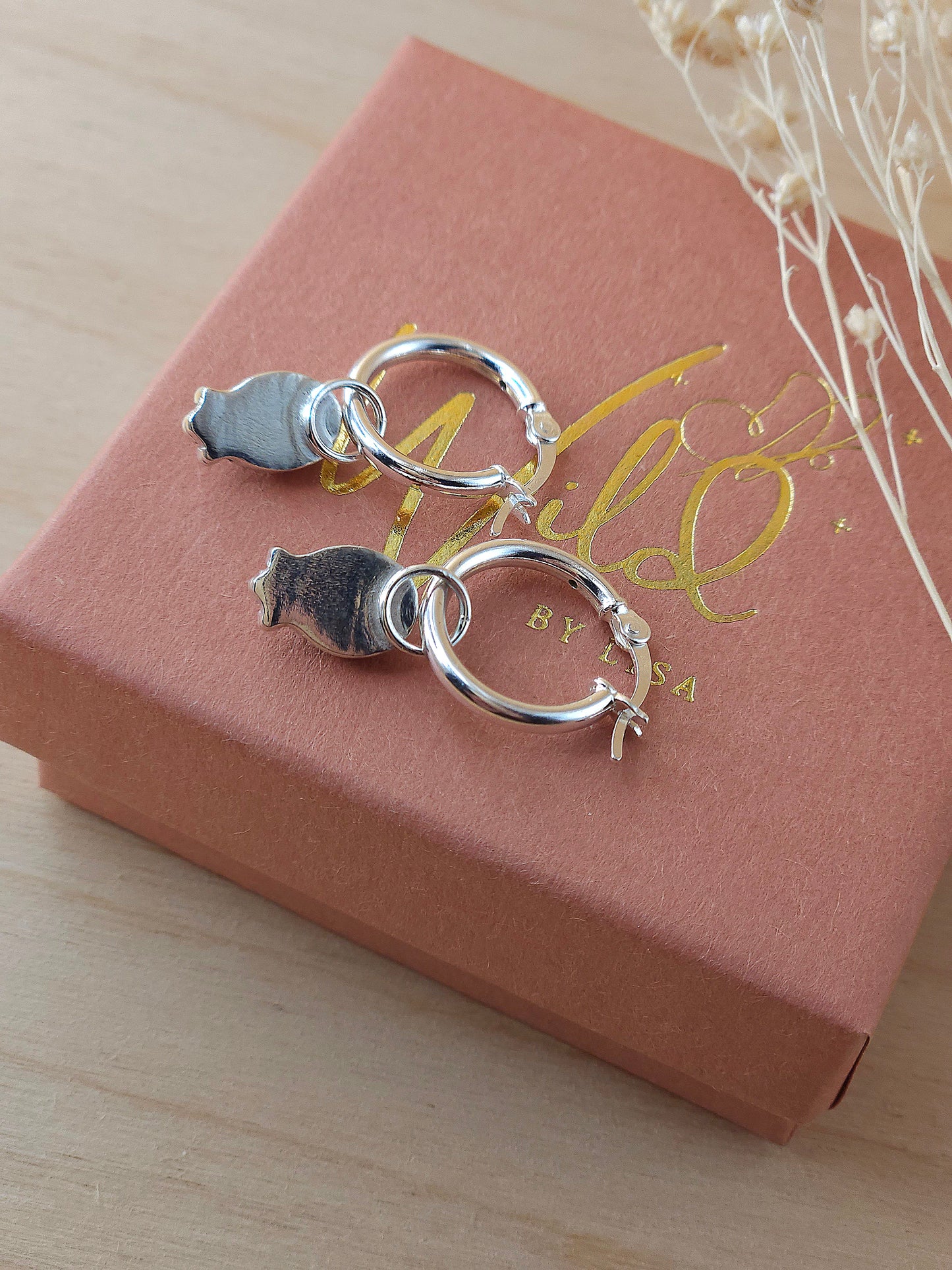 A pair of sterling silver gemstone hoop earrings displayed on a terracotta and gold coloured gift box showing the back of the gemstone setting.