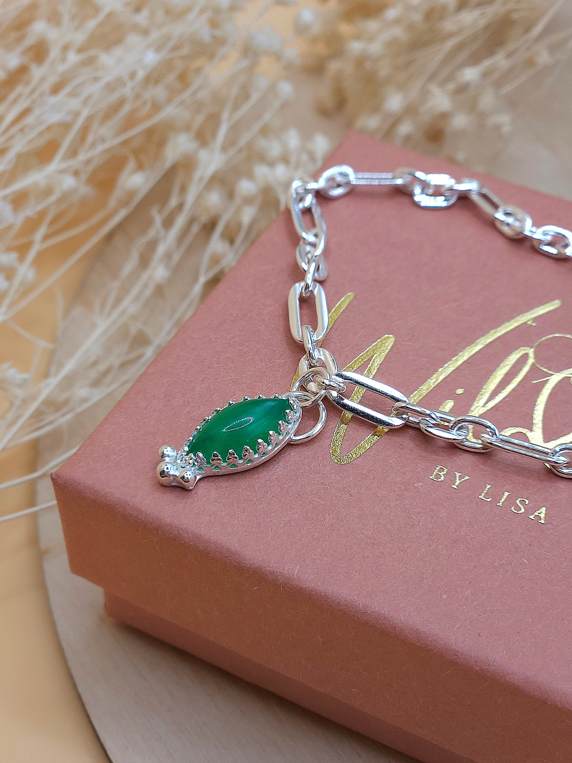 A silver link chain bracelet with a green Aventurine gemstone charm, displayed on a gift box with the brand name 'Wild by Lisa'.