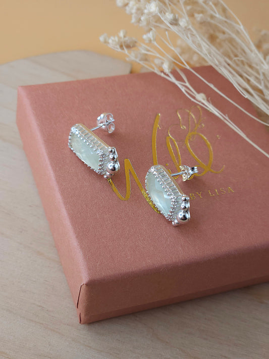 A pair of green Prehnite stud earrings with silver embellishments, displayed on a terracotta coloured gift box.