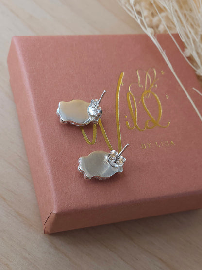 A pair of sterling silver stud earrings displayed on a terracotta coloured gift box showing the back of the earrings including the butterfly backing.
