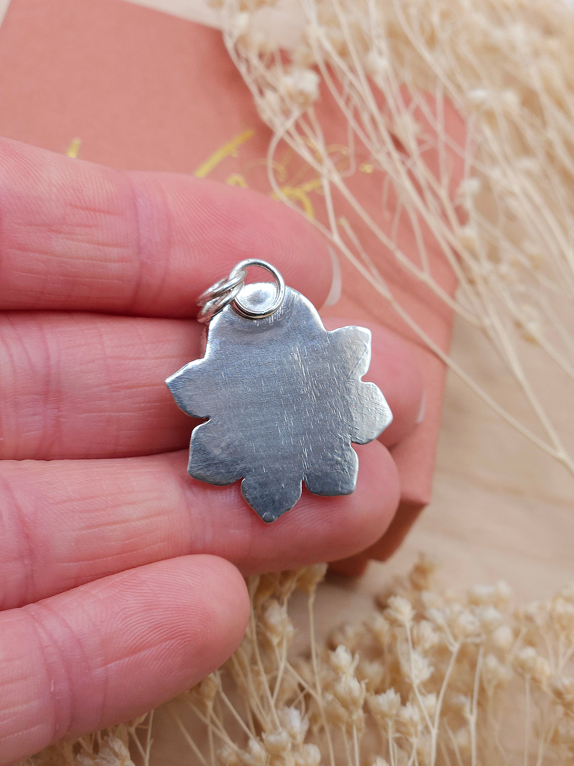 Shows the back of the flower pendant with a natural texture.