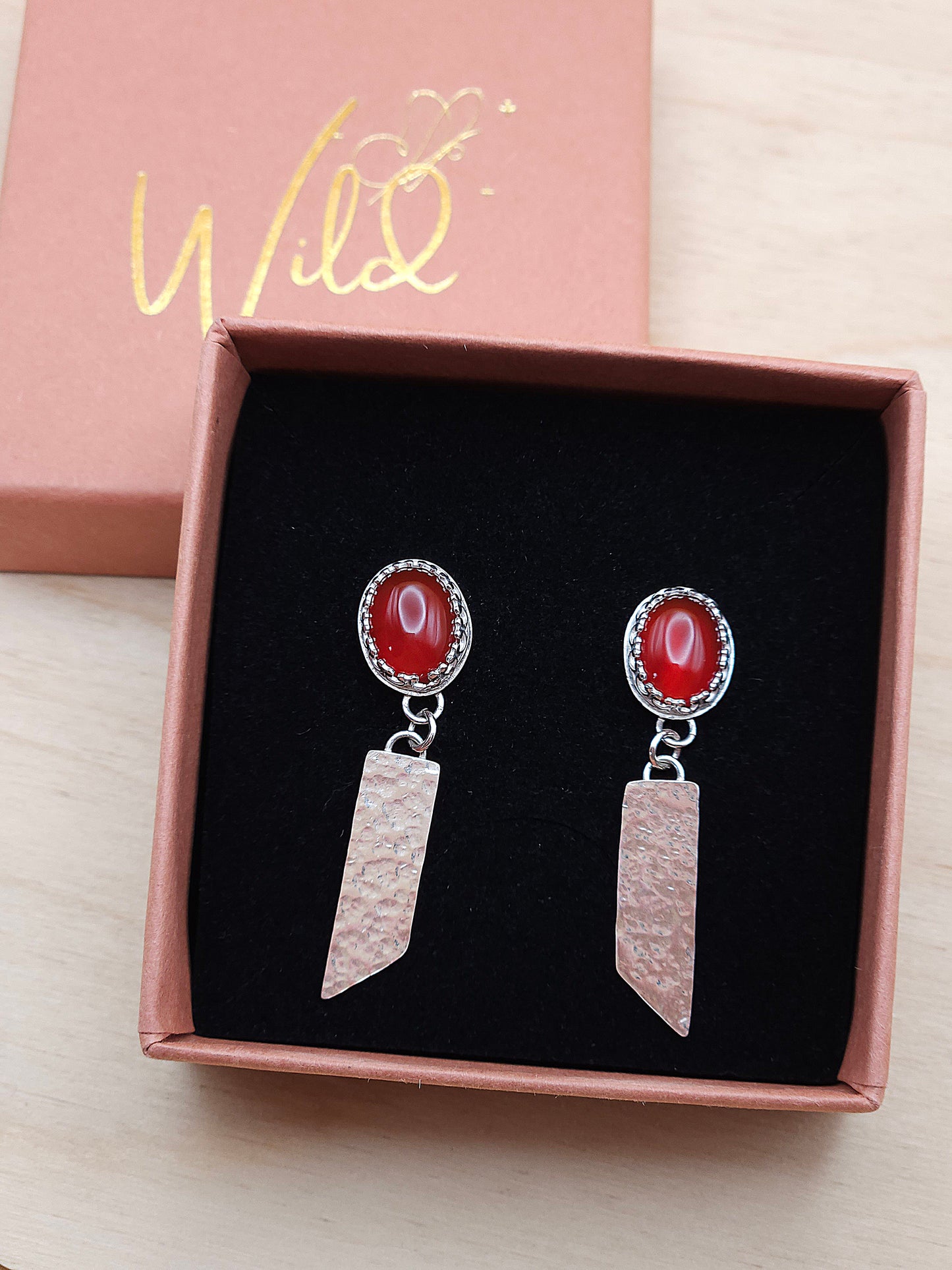 A pair of sterling silver carnelian hammered dangle earrings displayed in an open gift box.