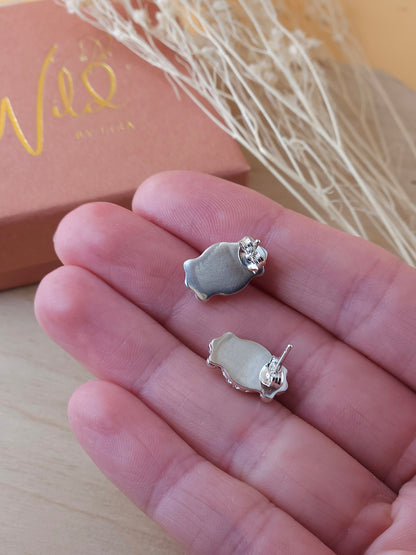 A hand holding a pair of sterling silver gemstone stud earrings show the back view including the butterfly backings.
